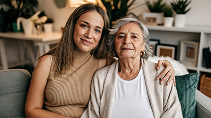 A younger and older woman sit together on a couch.