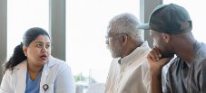 An older Black man and his grandson speak with a female doctor about what causes Alzheimer's.