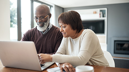 Caregiver assists person living with Alzheimer's with their finances on a laptop