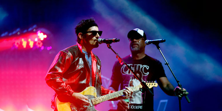 Brad Paisley and Darius Rucker perform onstage, wearing 1980s attire.