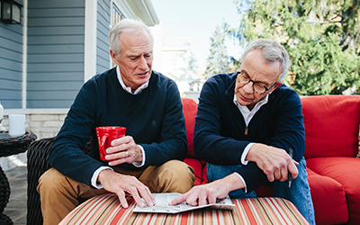 Two older men looking at a crossword puzzle together