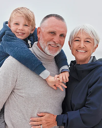 Father carrying son on his back with mother next to them smiling