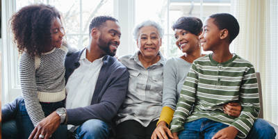 A smiling family surrounding an older woman