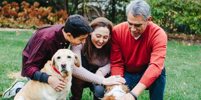 A family crouching down to pet two dogs