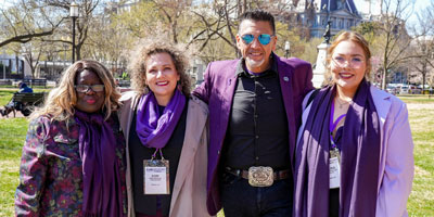 Celebrating and enthusiastic supporters holding #ENDALZ signs in front of a government building