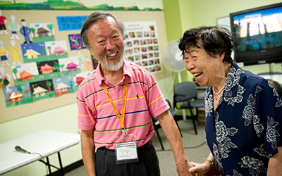 Older Asian man and woman laughing together in an adult day care center