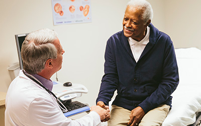 An older patient shaking hands with his doctor